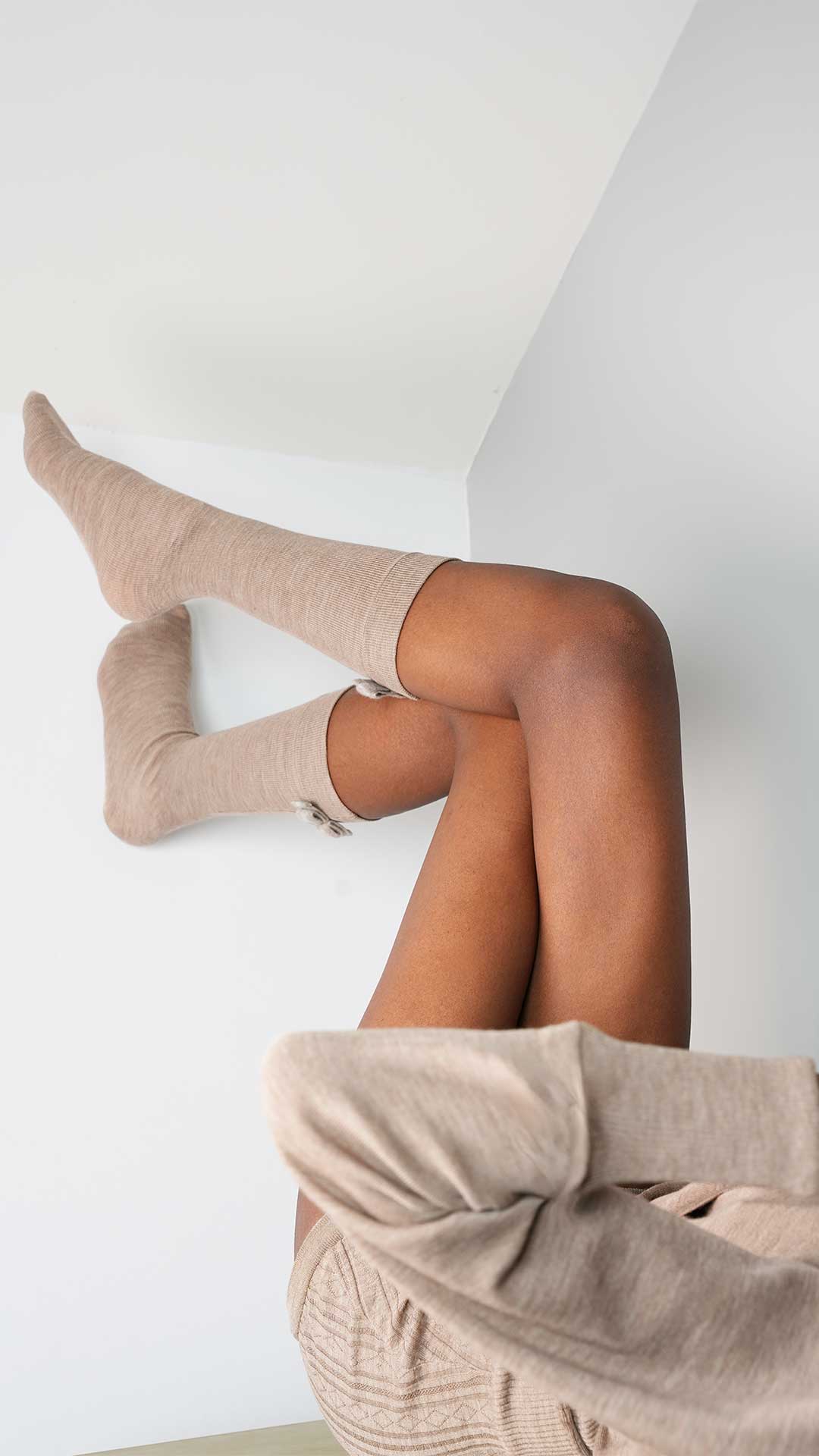 Person wearing beige knee-high socks and pants against a white background
